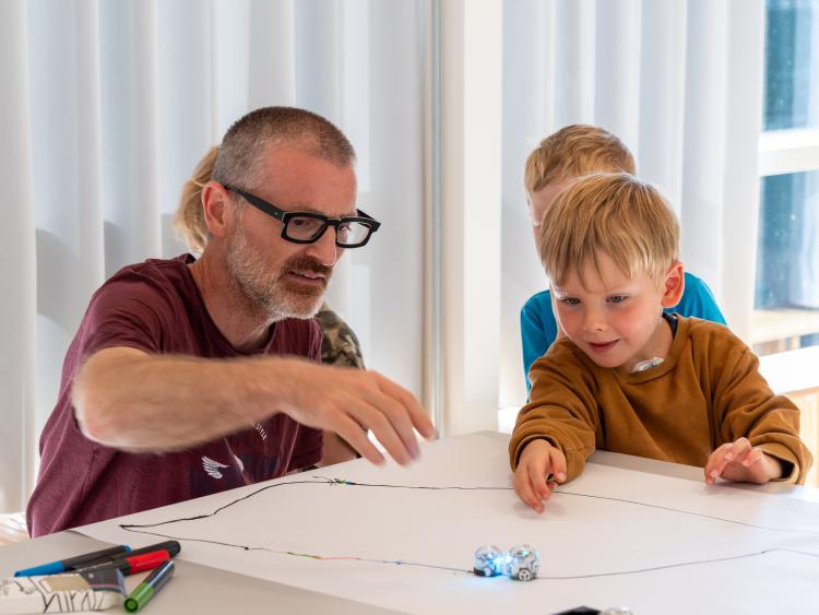 Pædagog og barn leger med robotter