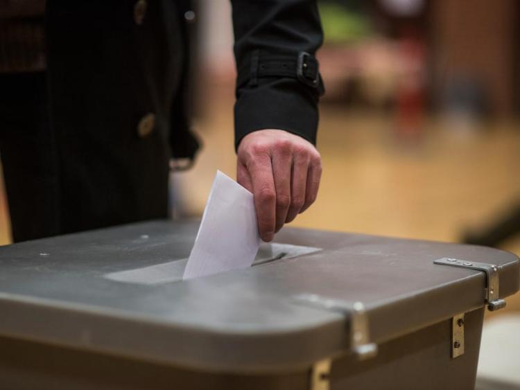 Hånd lægger en stemmeseddel i stemmeurnen