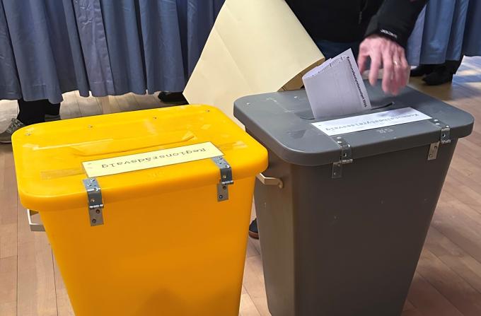 Vælger lægger stemmeseddel i stemmeurne. Der er en gul og en grå stemmeurne til henholdsvis regionsrådsvalget og kommunalbestyrelsesvalget.
