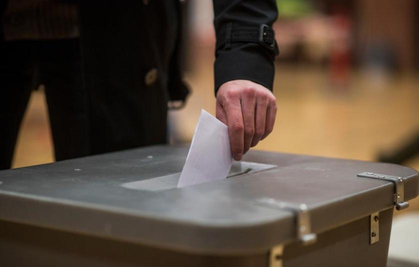 Hånd lægger en stemmeseddel i stemmeurnen